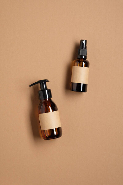 Эмбер стеклянные бутылки макет с пустыми этикетками на коричневом фоне. Конструкция упаковки насосных и распылительных контейнеров. Косметика для ванной. Плоский, вид сверху