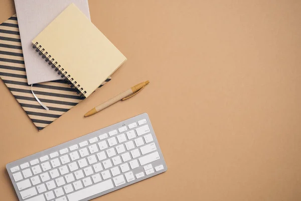 顶部视图 平面写字台与计算机键盘 纸质笔记本 钢笔褐色背景 现代工作空间 — 图库照片