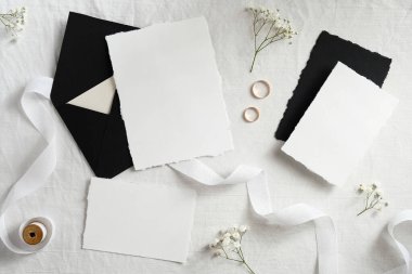 Pastel beyaz arka planda şık bir düğün kırtasiyesi. Davetiyeler, modeller, şablonlar. İskandinav tarzı asgari düzeyde. Düz yatış, üst görünüm.