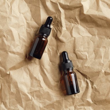 Kraft kağıdında kehribar cam damlatan şişeler. Doğal serumlar üst görünüm.