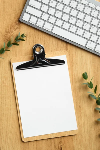 Houten Bureautafel Met Blanco Papieren Klembord Toetsenbord Eucalyptus Bladeren Bovenaanzicht — Stockfoto