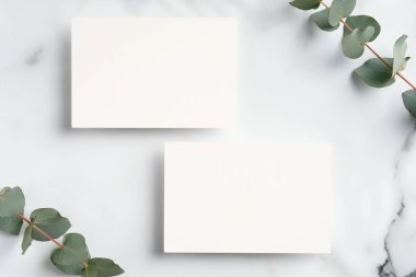 Düğün davetiyesi. Boş kağıt notlar ve okaliptüs yapraklarıyla mermer masa. Düğün konsepti. Düz konum, üst görünüm, kopyalama alanı
