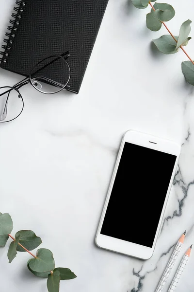 Elegant Feminint Skrivbord Med Smartphone Papper Anteckningsbok Eukalyptus Blad Glasögon — Stockfoto