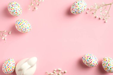 Renkli Paskalya yumurtaları, tavşancık ve bahar çiçekleri pastel pembe arka planda yatıyordu. Yukarıdan görüntüle, boşluğu kopyala.