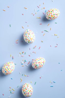 Pastel mavi arka planda renkli paskalya yumurtaları. Düz konum, yukarıdan görünüm.