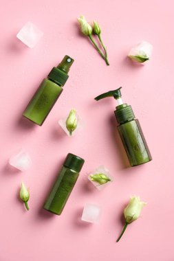 Bahar çiçekleri ve buz küpleriyle hazırlanmış doğal organik SPA kozmetik ürünleri. Üst görünüm bitkisel cilt ürünleri pembe arka planda