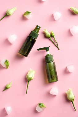 Set of natural organic cosmetics with ice cubes and flowers on pink background. SPA beauty products for skincare, body and hair care. Flat lay, top view