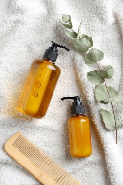 Banyodaki beyaz havluya şampuan ve duş jeli. Düz yatış, üst görünüm.