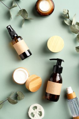 SPA bitkisel kozmetik seti ve yeşil arka planda okaliptüs yaprakları. Doğal organik güzellik ürünleri tasarımı, markalaşma. Düz yatış, üst görünüm.