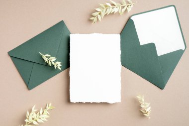 Düğün kartı ve zarflar kurumuş yapraklarla süslenmiş. Düz konum, üst görünüm, kopyalama alanı.