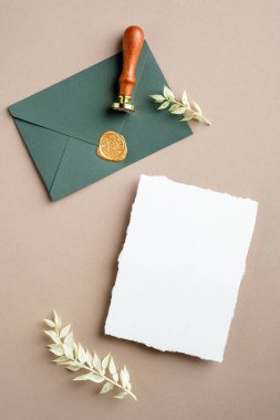Düğün kırtasiyesi sahnesi. Boş tebrik kartı, balmumu mühür damgalı, kurumuş çiçekler. Düz konum, üst görünüm, kopyalama alanı.
