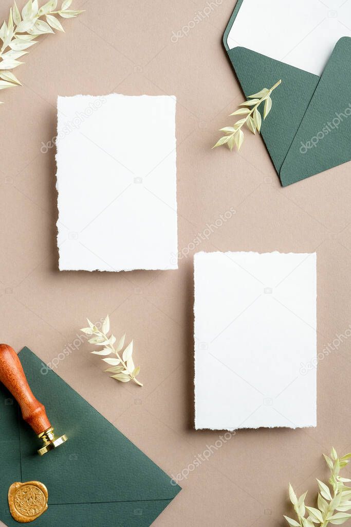 Flat lay wedding invitation cards, green envelope with seal wax stamp, dried flowers on pastel beige background. Wedding stationery set top view.