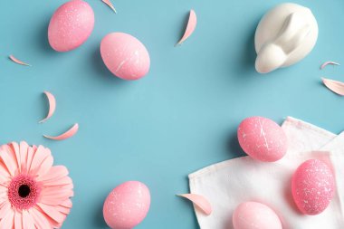 Pembe Paskalya yumurtaları, bahar çiçekleri, turkuaz arka planda tavşan. Düz döşeme, üst manzara, moda renkler. Mutlu Paskalyalar.