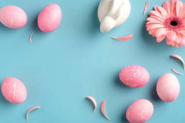 Modern pembe paskalya yumurtaları, bahar çiçeği, turkuaz arka planda Paskalya tavşanı. Düz konum, üst görünüm, kopyalama alanı.