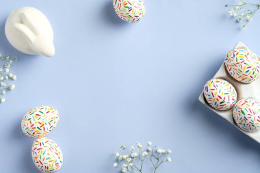 Mutlu Paskalyalar. Renkli benekli Paskalya yumurtaları, bahar çiçekleri, Paskalya tavşanı. Düz konum, üst görünüm, kopyalama alanı.