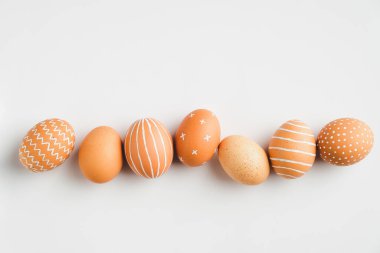 Beyaz arka planda sıra sıra boyanmış Paskalya yumurtaları. Düz yerde, üst tarafta. Zarif, basit, modern stil..