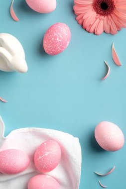 Mutlu Paskalyalar. Düz pembe yumurtalar, Paskalya tavşanı, turkuaz arka planda çiçek ve taç yaprakları.