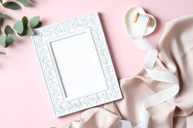 Vintage photo frame mockup, eucalyptus leaves, ribbon, fabric on pink background. Happy Mothers day concept.