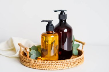 Kehribar cam pompa şampuan şişeleri ve rattan tepside sıvı sabun. SPA doğal organik kozmetik seti. Kişisel hijyen ürünleri..