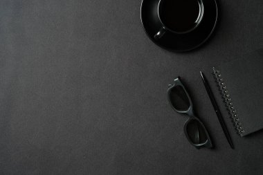 Bir fincan kahve, kağıt defter, bardaklar, deri arka planda kalem olan şık bir ofis masası. Düz konum, üst görünüm, kopyalama alanı. Lüks serbest meslek alanı.