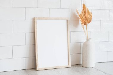 Dikey poster maketi ve vazoda kurumuş çiçekler. Arka planda tuğla kiremitler var. İskandinav ev dekoru, İskandinav tarzı. Fotoğraf çerçevesi maketi.