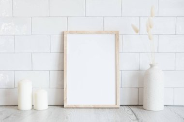 Oturma odasının iç tasarımı, fotoğraf çerçevesi, vazoda kurumuş çiçekler, mumlar. Arka planda tuğla kiremitler var. İskandinav, İskandinav tarzı.