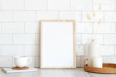 Kahvaltı hala hayattadır. Boş resim çerçevesi maketi, bir fincan kahve, bir defter, kurumuş çiçekler ve ahşap masa. Arka planda tuğla kiremitler var. Hygge, İskandinav tarzı..