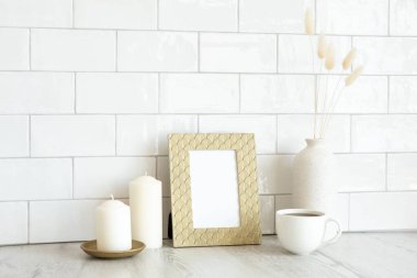 Durgun bir hayat, resim çerçeveli iç mekan, mumlar, bir fincan kahve, kurutulmuş çiçek vazosu. Arka planda tuğla kiremitler var. Hygge, İskandinav tarzı..