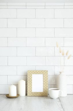 İskandinav tarzı oturma odası tasarla. Resim çerçevesi, mumlar, bir fincan kahve, kurutulmuş çiçekler. Arka planda tuğla fayanslar. Kuzey tarzı.