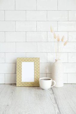 Boş fotoğraf çerçevesi maketi, bir fincan kahve, oturma odasındaki masada duran vazodaki kuru çiçekler. İskandinav, İskandinav tarzı.