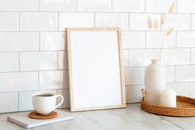 Masadaki beyaz resim çerçevesi ve ev dekorasyonu. İskandinav oturma odası iç tasarımı. Kuzey tarzı.