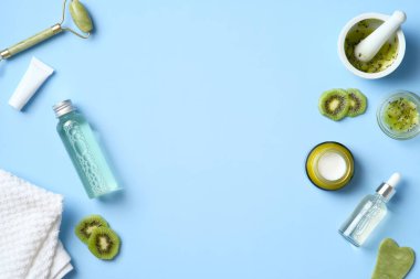 Mavi arka planda kivi bulunan doğal organik kozmetikten yapılmış çerçeve. Bitkisel cilt ürünleri seti. Düz yatış, üst görünüm