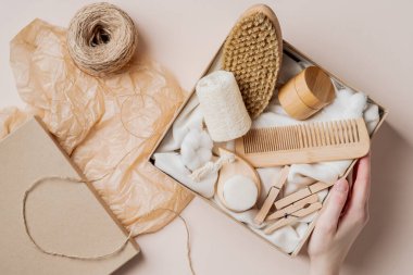 Preparing self care package. Beauty box with body brush, wooden hair comb, moisturizer. Flat lay, top view.