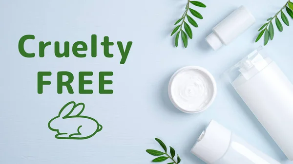 Cruelty free cosmetics set on blue background. Hair care herbal cream in jar, shampoo bottle, shower gel container and green leaves. No animal testing