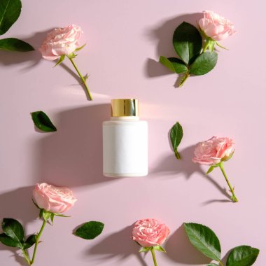 Rose flower buds and cosmetic lotion bottle on pink background. Luxury SPA cosmetic concept,