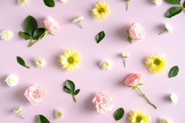 Floral composition on pink background. Roses, gren leaves and daisy flowers top view. Flat lay.