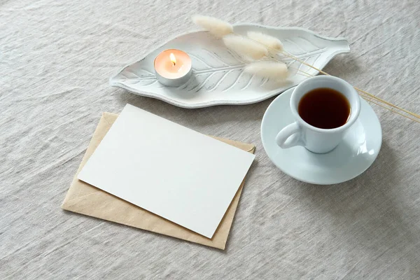 Romantic breakfast concept. Blank postcard mockup, envelope, cup of coffee, candle, dried grass top view. Boho style still life.