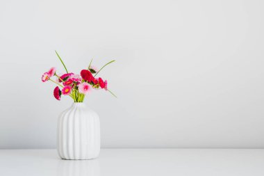 Beyaz arka planda vazoda duran bir buket pembe çiçek. Çiçekli ev dekorasyonu. Asgari biçim.