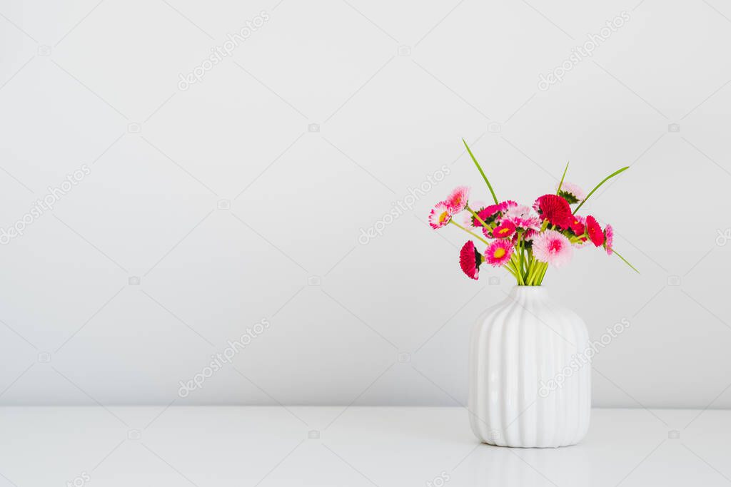 Pink spring flowers in vase on white background. Minimal style.