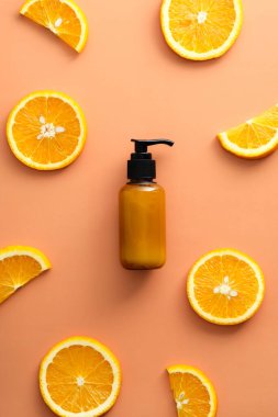 C vitamini kozmetik losyon şişesi ve arka planda portakal dilimleri. Citrus güzellik ürünü tasarımı.