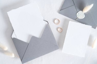 Düğün davetiyesi şablonu. Üst görünüm boş kağıt kart, altın yüzükler, beyaz arka planda kurumuş çiçekler..