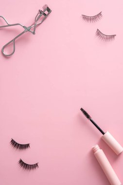 Makyaj malzemelerinden yapılmış çerçeveli pembe. Üst görünüm rimel, takma kirpik, bigudi..