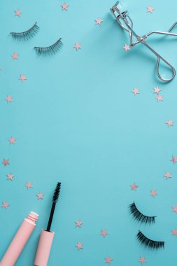 Mascara with false eyelashes and tools on blue background. Flat lay, top view.