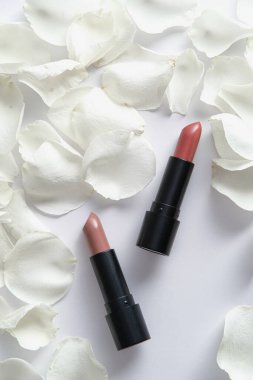 Beyaz arka planda ruj ve gül yapraklarıyla düz bir kompozisyon.