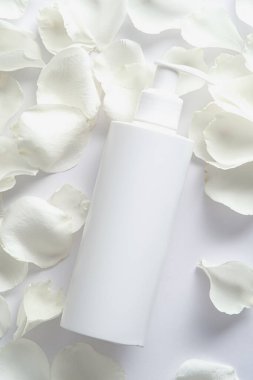 Şampuan şişesi maketi ve beyaz arka planda gül yaprakları. Kozmetik marka, tasarım. Düz yatış, üst görünüm.