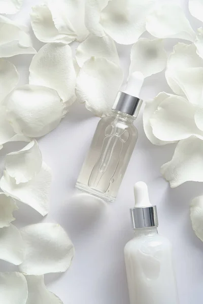 白色背景的精油瓶和玫瑰花瓣 平躺在地上 俯瞰四周 — 图库照片
