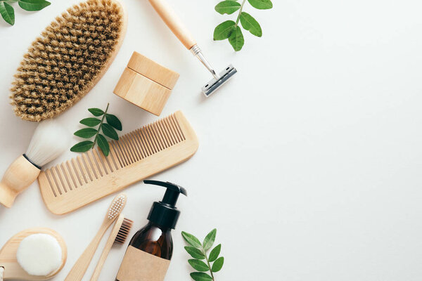 Комплект экологически чистых принадлежностей для ванной и косметики с зелеными листьями на белом фоне. Устойчивый образ жизни, безпластиковая концепция. Плоский, вид сверху.