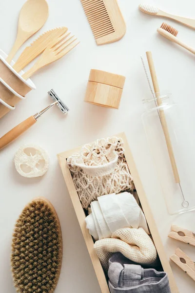 Beyaz arka planda çevre dostu sıfır atık aksesuarları. Tek kullanımlık çatal bıçak takımı, bambu banyo aletleri, alışveriş torbaları, üst manzara..