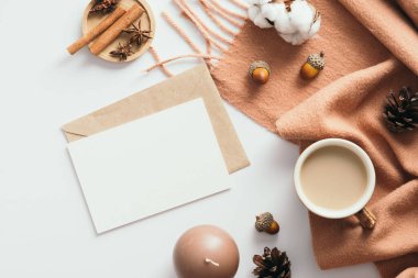 Sonbahar kompozisyonu. Eşarplı kadın masası, kahve fincanı, beyaz arka planda zarflı boş kağıt maketi. Düz yerde, üst tarafta. İskandinav, higge, konforlu ev kavramı