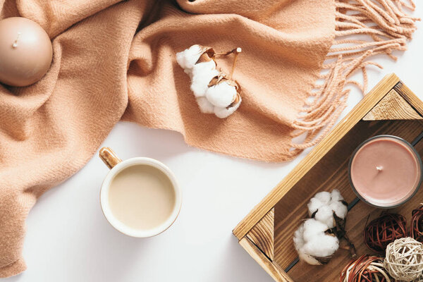Cozy home desk table with brown scarf, coffee cup, decorations on wooden white background. Top view, flat lay. Autumn composition. Nordic hygge style concept.